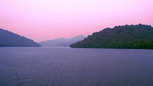 Golden hour sea creek view in thane , maharashtra, hills in the backgroud with pink sky and water 
