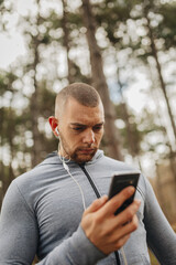 Fototapeta premium Man looks at phone while standing in forest during daytime