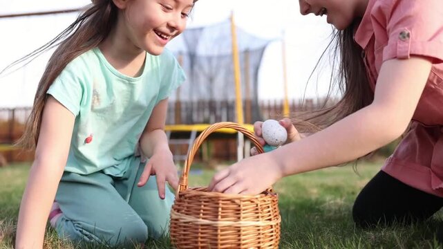 spring fun - finding eggs for easter outdoor in countryside. Happy children sitting on grass with found eggs and basket on sunny day. easter hunt in backyard.