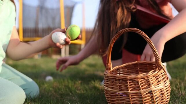 spring fun - finding eggs for easter outdoor in countryside. Happy children sitting on grass with found eggs and basket on sunny day. easter hunt in backyard.