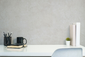 Minimal desk scene with coffee mug on notebook, pencil holder, and succulent; white glossy table...