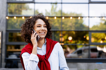 Smiling beautiful woman talking on mobile phone on the street outdoors