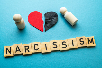 Concept of narcissism, expressed with a wooden alphabet and a torn heart. Narcissism and gaslighting.
