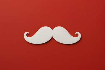 White paper mustache cutout placed on a vibrant red background, creating a playful and whimsical atmosphere, perfect for festive occasions and creative projects