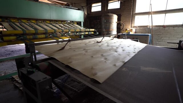 Valmiera, Latvia - October 01, 2025: Industrial machinery processes sheets of material in a factory, showcasing continuous action and production flow