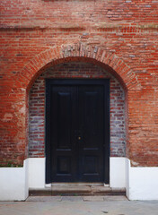Fototapeta premium Old wooden entrance door on a red brick wall. Old, antique, and historic building
