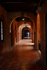 Fototapeta premium The corridor of an old building made of sturdy red brick. The long corridor forms a leading line. Perspective photo of the building. 