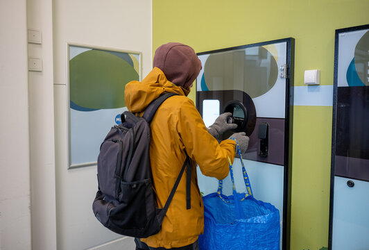 Person using self service bottle return machine for recycling indoors