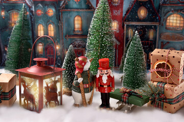 Christmas arrangement with nutcracker and penguin figurines standing in the old town on snowy evening