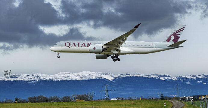 Geneva, Switzerland - november 29, 2025 : sign and logo on an Airbus A350 - 300 of Qatar Airways landing st Geneva airport  with backdrop of snow-covered mountains	