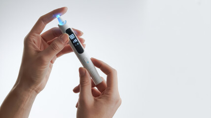 Medical and Technology. A person holding a modern device with a glowing tip, likely related to health or beauty, featuring a digital display and sleek design.