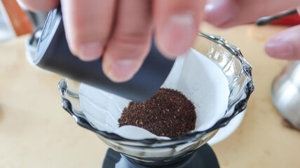 close up of adding grinded coffee bean powder to the filter paper in a transparent Pour Over Filter 