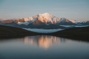 Snow-capped mountain range reflected in calm lake at dawn