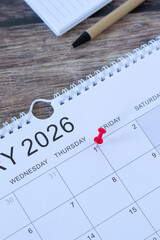 January first 2026 new year calendar date with a pin, notebook, and pen on wooden background. Top view. Business goals reminder, annual planning concept.