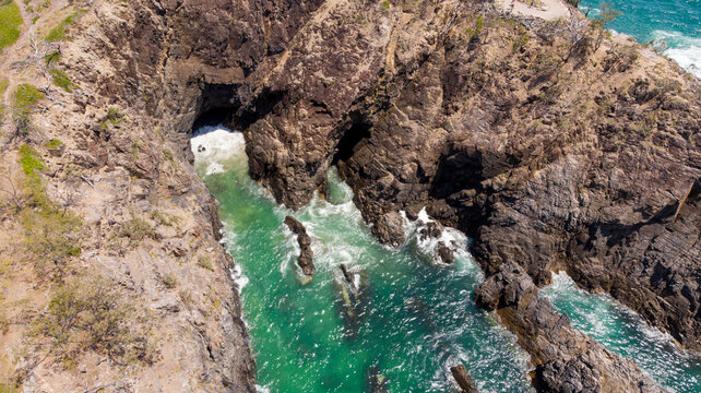 Aerial view of the rugged cliffs embracing the turquoise waters near Hell's Gates, creating a dramatic coastal scene, Noosa Heads, Queensland, Australia.