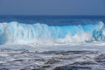 Powerful Blue Ocean Wave Breaking on Rocky Shore