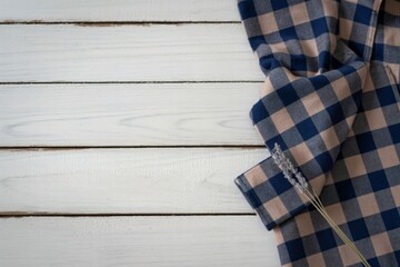 Close up of a folded blue and tan plaid shirt on a white wooden background