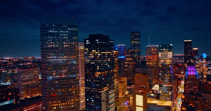 High-rises and skyscrapers of Houston, Texas, USA against dark cloudy sky. Descending in the downtown of metropolis at night.