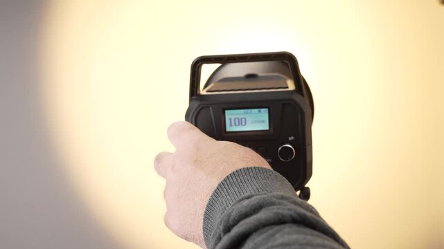 The brightness of a studio LED light is increased using rear controls. The display clearly shows changing intensity values during adjustment.