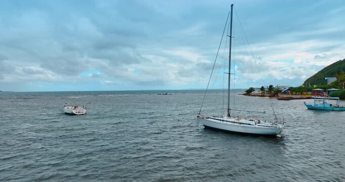 Flight over grey turbulent waterscape on cloudy day. Boats are on the seascape at the shore of Puerto Rico. Dramatic clouds cover the sky on the windy day.