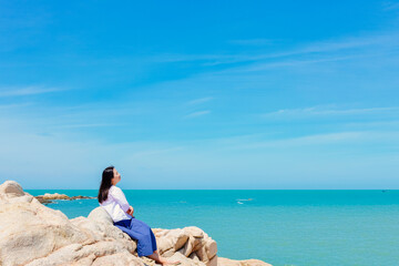 One Asian woman enjoying the tropical beach and rock landscape of Dajiao Park in Qizi Bay, Changjiang, Hainan, China