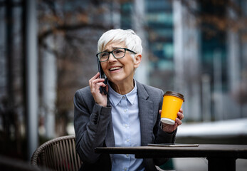 Business woman talking on phone while holding coffee cup