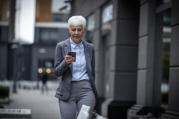 Businesswoman walks while looking at phone outside