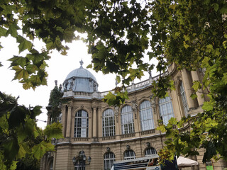 A view of palace in the center of Budapest surrounded by green trees and cozy yard. Architectural and cultural heritage of Europe. Travel the world. Visiting famous historical sights.