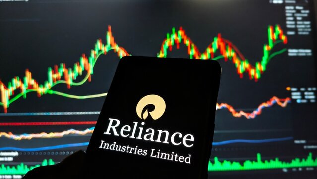 Reliance industries limited logo displayed on a smartphone screen against a backdrop of stock market trading charts and graphs  , New York City, 15 December 2025