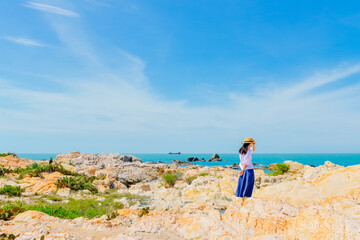 Naklejka premium One Asian woman enjoying the beautiful tropical beach and ocean landscape of Dajiao Park in Qizi Bay (Qiziwan), Changjiang, Hainan, China