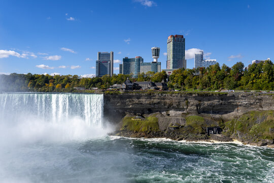 View of the powerful cascade of Niagara Falls crashing into the churning river below, framed by the skyline, Niagara Falls, Ontario, Canada.