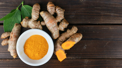 Fresh turmeric and powder on a white bowl on wooden background. cope space