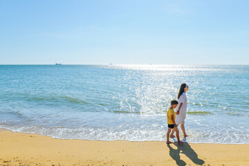One Asian woman and her boy walking on Yulinzhou (Fish scale Delta, Yulin Bay) beach in Basuo Town, Dongfang, Hainan, China © sweetriver