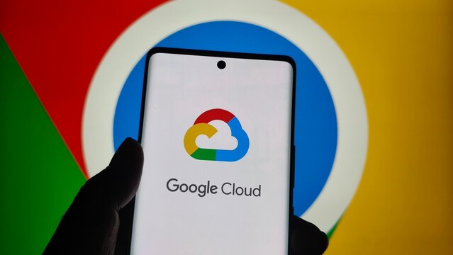 Smartphone displaying google cloud logo and text in front of a large, colorful google chrome browser icon background  , New York City, 15 December 2025