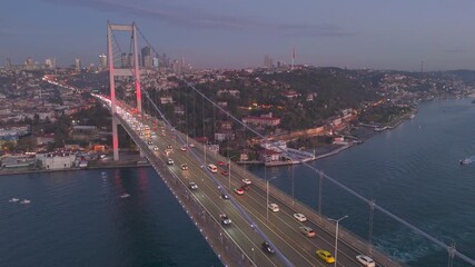 Istanbul Cityscape and Bosphorus Bridge (July 15 Martyrs Bridge) with big trafic. Aerial drone night view of the Bosphorus Bridge in sunrise. Ships passing Istanbul Canal or Bosphorus canal.