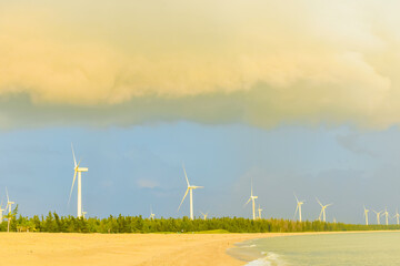 Beautiful sunset on beach with wind turbines installed along Hainan Coastal Scenic Highway in Dongfang city, Hainan, China