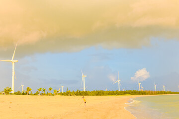 Beautiful sunset on beach with wind turbines installed along Hainan Coastal Scenic Highway in Dongfang city, Hainan, China