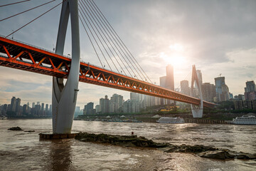 Red arch bridge over a river with a modern city skyline in Chongqing.