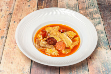 A hearty dish of Madrid-style tripe, featuring chunks of tripe, Burgos black pudding, chorizo, and ham in a rich, spiced stew with paprika and cumin