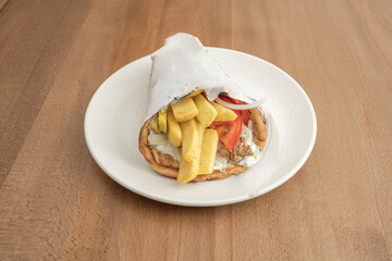 Chicken shawarma with garlic and lemon sauce, served with a side of French fries and tomato salad