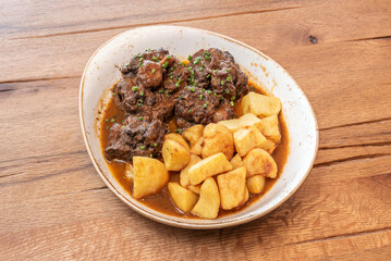 Traditional oxtail stew served in an individual bowl, with a reduced and glossy sauce, ideal for dipping with artisan bread
