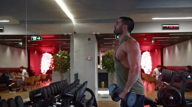 Athletic young man with battle rope doing exercise in functional training fitness gym.
