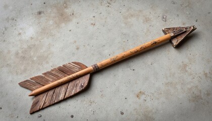 Wooden arrow with feather fletching lying on a concrete surface  