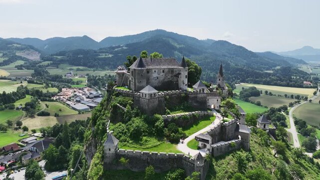 Cinematic drone footage capturing Hochosterwitz Castle on hilltop, fortified walls, dramatic cliffs, summer colors, sweeping aerial movement, historical landmark atmosphere