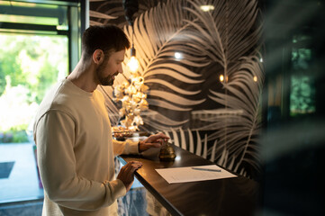 Tall dak-haired man standing at the reception desk in the hotel