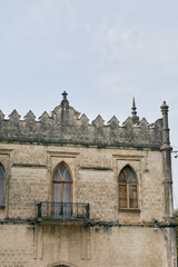 Historic stone building with arched windows and a small balcony, showcasing medieval architecture and weathered texture against a clear sky.
