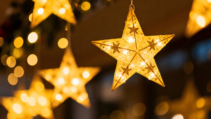 Close up of glowing star shaped lights hanging against a bokeh background.