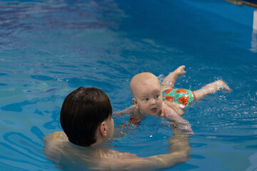 The baby takes a breathe before diving under water.