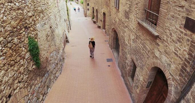 Woman Strolling in a Picturesque San Gimignano Street Alley, Tuscany, aerial view