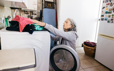 Senior woman doing laundry with washing machine